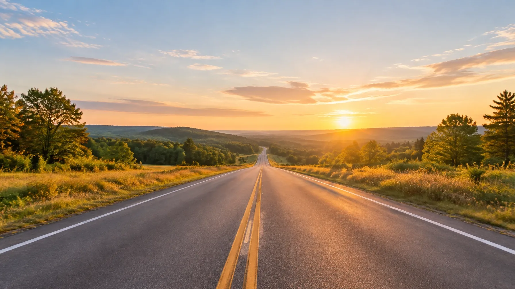 Open rural road receding toward a hopeful golden-hour horizon