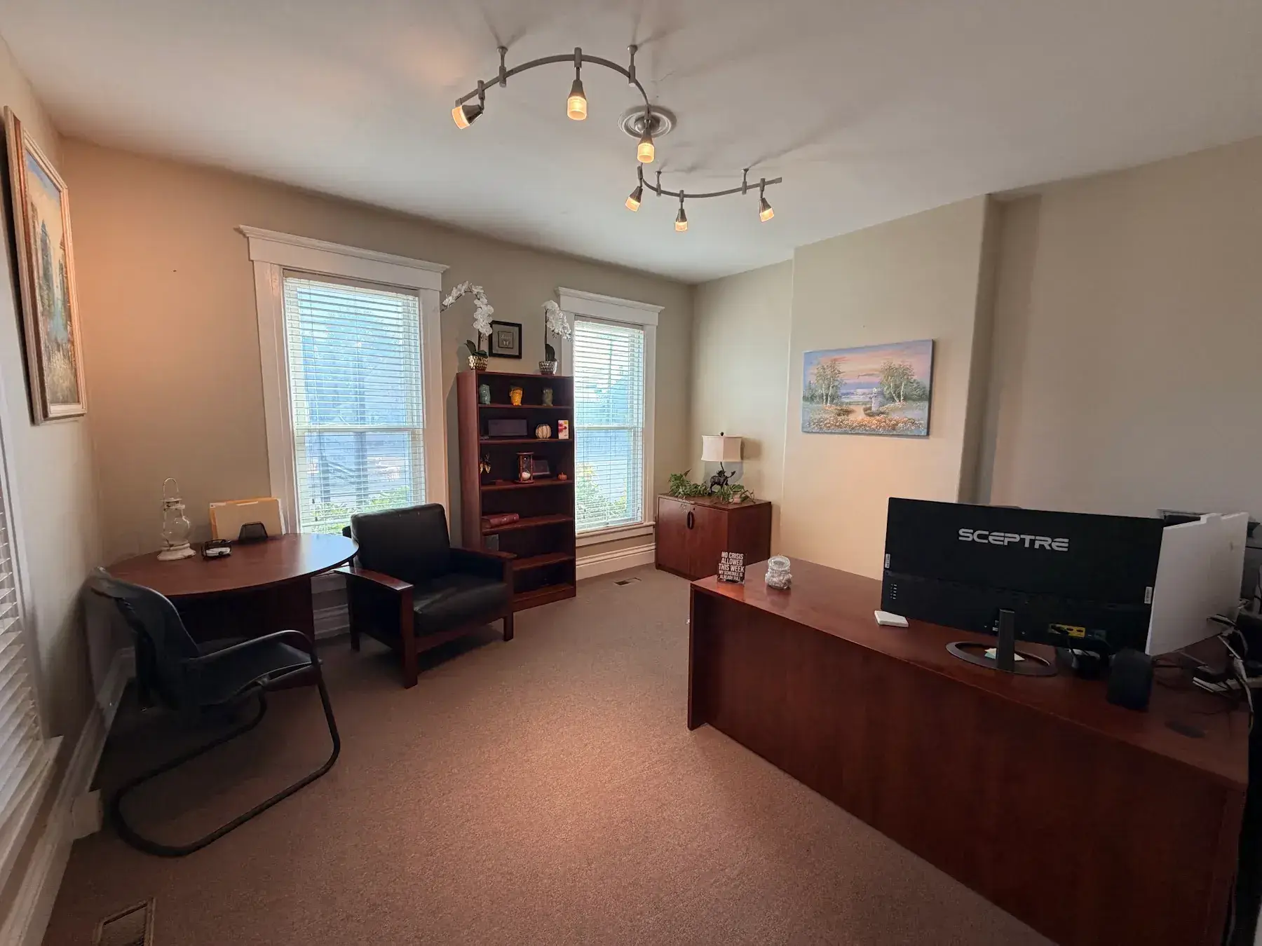Donna’s downstairs office with a desk, chairs, and wall art at the Concord, NH office