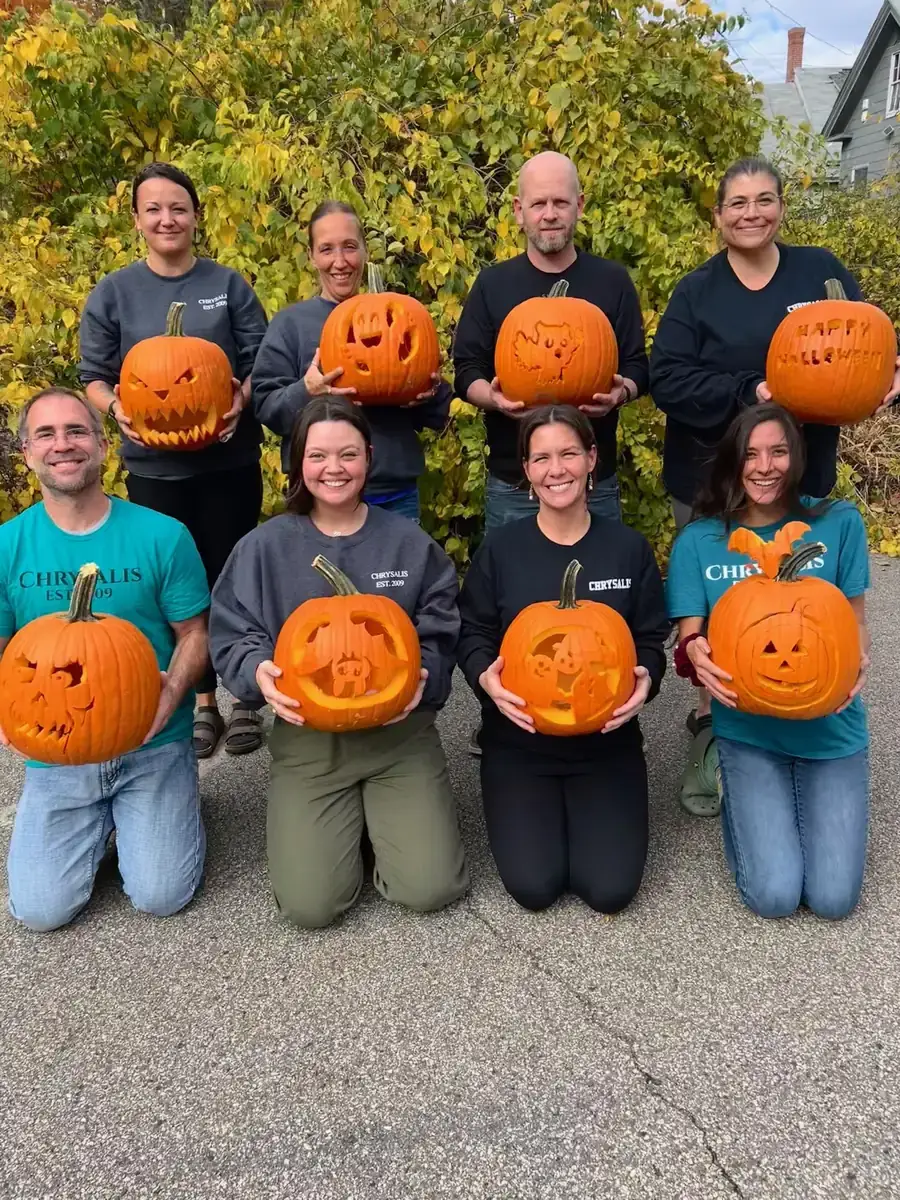 Chrysalis Recovery Center staff gathered together outdoors with carved pumpkins
